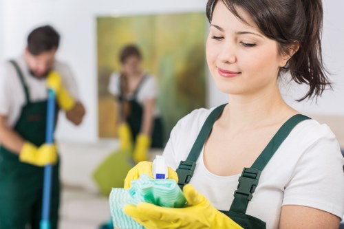 Professional cleaner sanitizing shared hallway surfaces